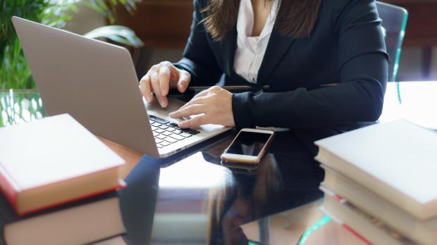 A female conveyancer sits at her desk using her laptop