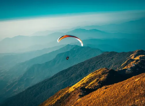 Person paragliding over hills